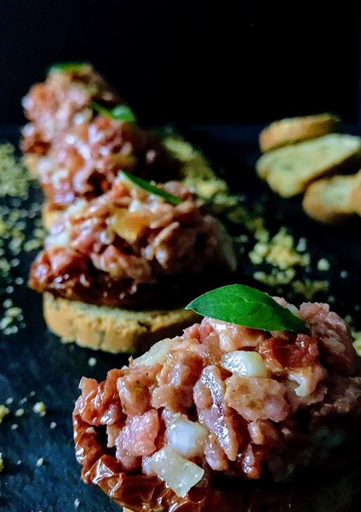 Una foto de Tartar de fuet con tomates secos en aove y polvo de morro tostado