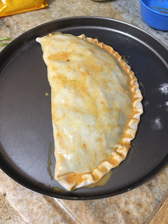 Una foto de Empanada gigante de cebolla, tomate y queso envuelta en hojas de espinacas