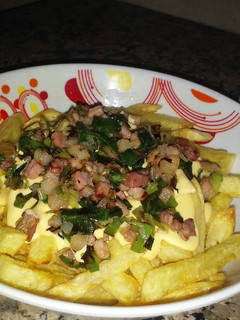 Una foto de Papas fritas con salsa de cheddar, panceta y cebolla de verdeo