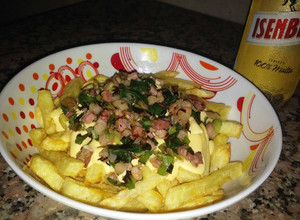 Una foto de Papas fritas con salsa de cheddar, panceta y cebolla de verdeo