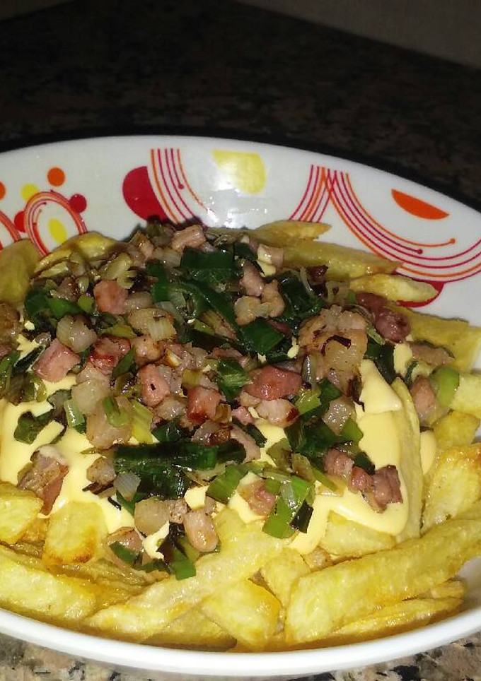 Una foto de Papas fritas con salsa de cheddar, panceta y cebolla de verdeo