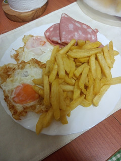 Una foto de Huevos fritos con papas fritas y mortadela