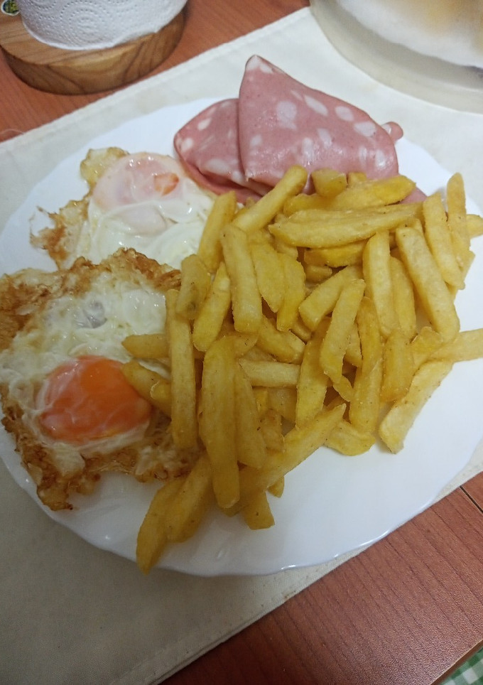 Una foto de Huevos fritos con papas fritas y mortadela