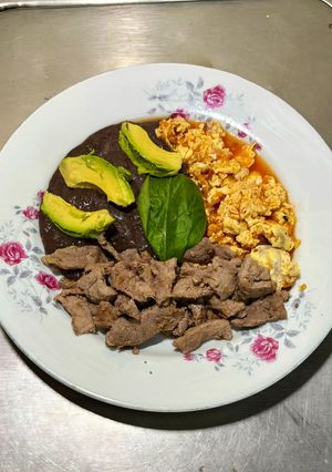 Una foto de Huevos Revueltos, Bistec y Frijoles Negros Refritos