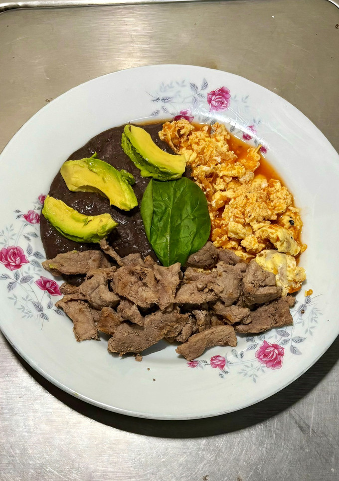 Una foto de Huevos Revueltos, Bistec y Frijoles Negros Refritos