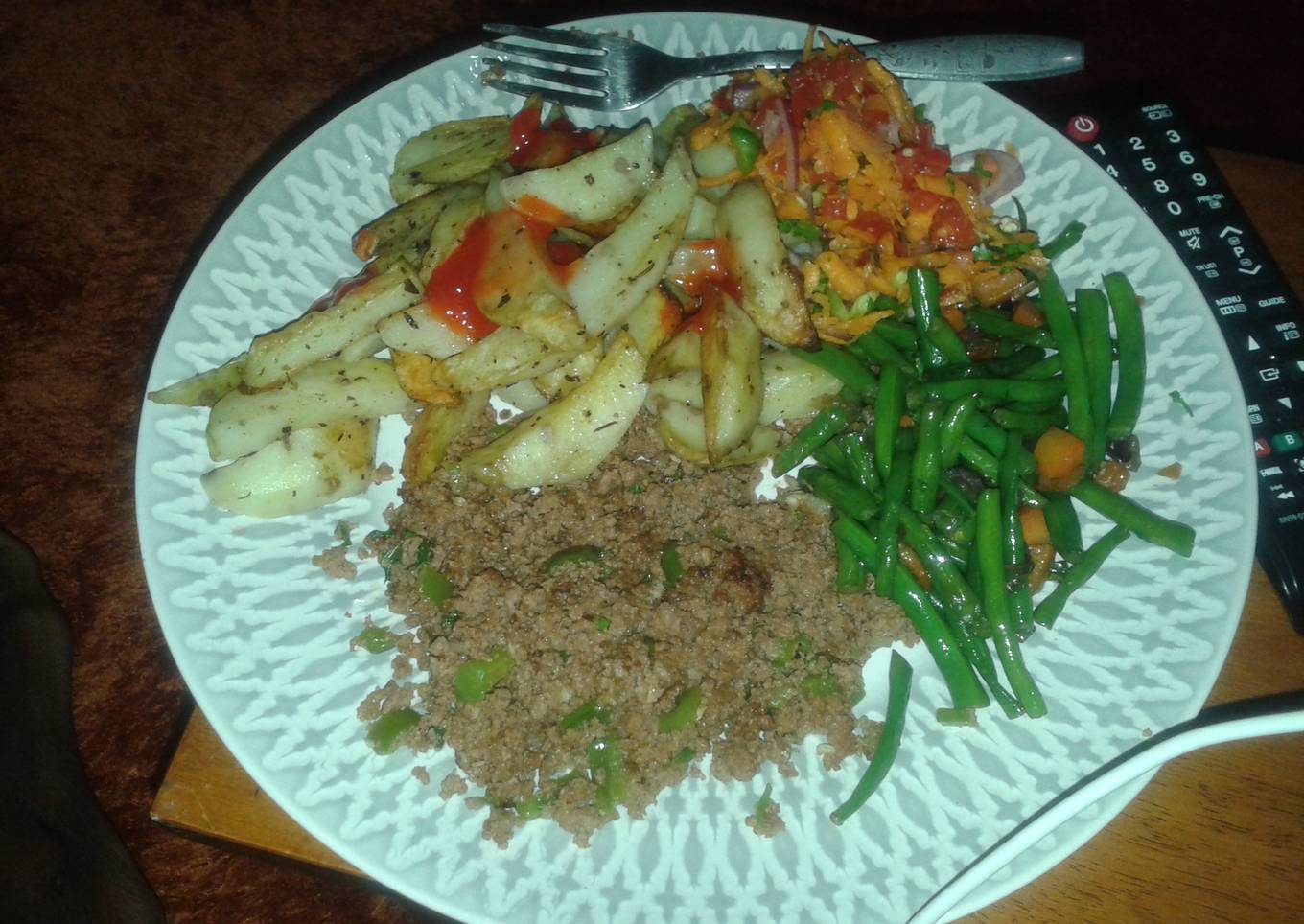 Potato wedges served with minced meat, fried French beans and kachumbari