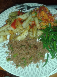 A picture of Potato wedges served with minced meat, fried French beans and kachumbari.