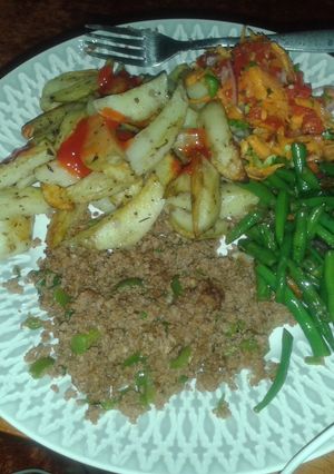 A picture of Potato wedges served with minced meat, fried French beans and kachumbari.
