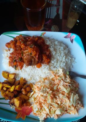 A picture of White rice with stew,fried plantain and Coleslaw.