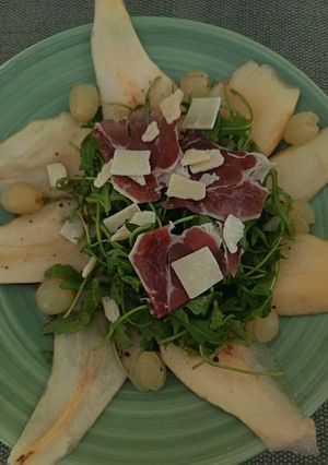 Una foto de Ensalada de peras, uvas y rúcula con viruta de ibérico de bellota y parmesano y su aliño