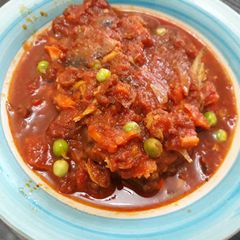 A picture of Tomatoes stew with fish and green peas.