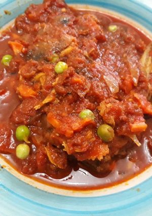 A picture of Tomatoes stew with fish and green peas.
