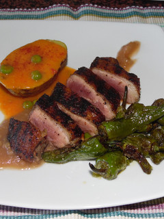 Una foto de Pechuga de pato asada con pimientos del padrón, papa con salsa de carne guisantes y puré de manzana