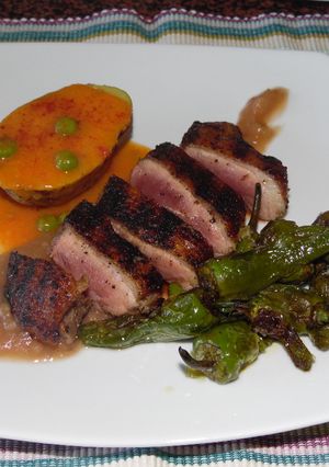 Una foto de Pechuga de pato asada con pimientos del padrón, papa con salsa de carne guisantes y puré de manzana