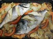 Una foto de dorada al horno con cebolla y tomate