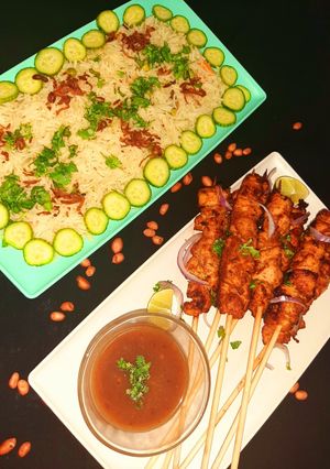 A picture of Chicken satay with peanut sauce and mixed vegetable rice.