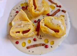 Foto di Tortelloni Ripieni al Culatello su Vellutata di Parmigiano con Guanciale Croccante e Pepe Rosa
