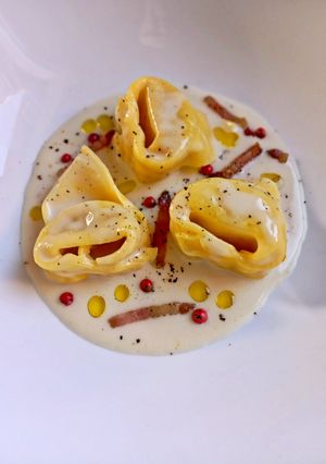Foto di Tortelloni Ripieni al Culatello su Vellutata di Parmigiano con Guanciale Croccante e Pepe Rosa