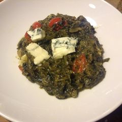 A picture of Dandelion Ka Saag. with grape tomatoes and blue cheese.