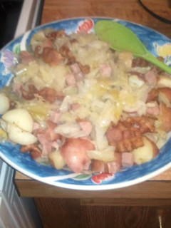 A picture of steamed cabbage with bacon,ham, red potatos.