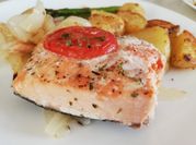 Una foto de salmón al horno con tomate y cebolla