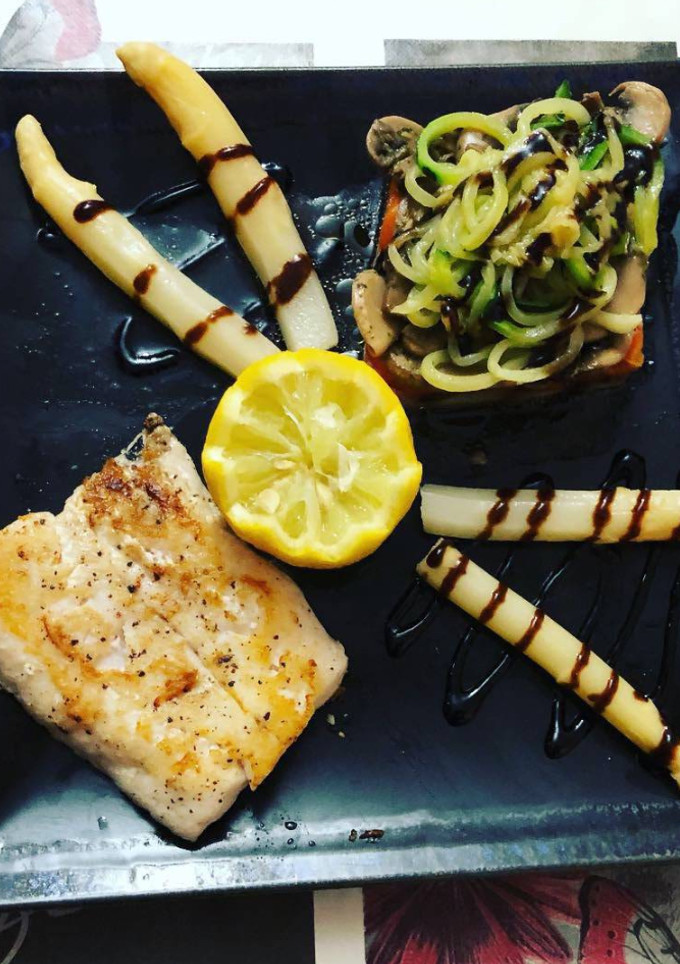 Una foto de Merluza a la plancha con rombo de coliflor, pimientos, champiñones, calabacín y espárragos