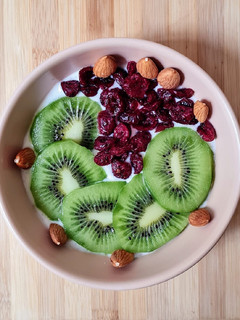 Una foto de Smoothie bowl de yogur de canela, con kiwi fresco, cranberries y almendras remojadas