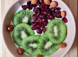 Una foto de Smoothie bowl de yogur de canela, con kiwi fresco, cranberries y almendras remojadas