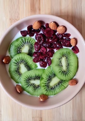 Una foto de Smoothie bowl de yogur de canela, con kiwi fresco, cranberries y almendras remojadas