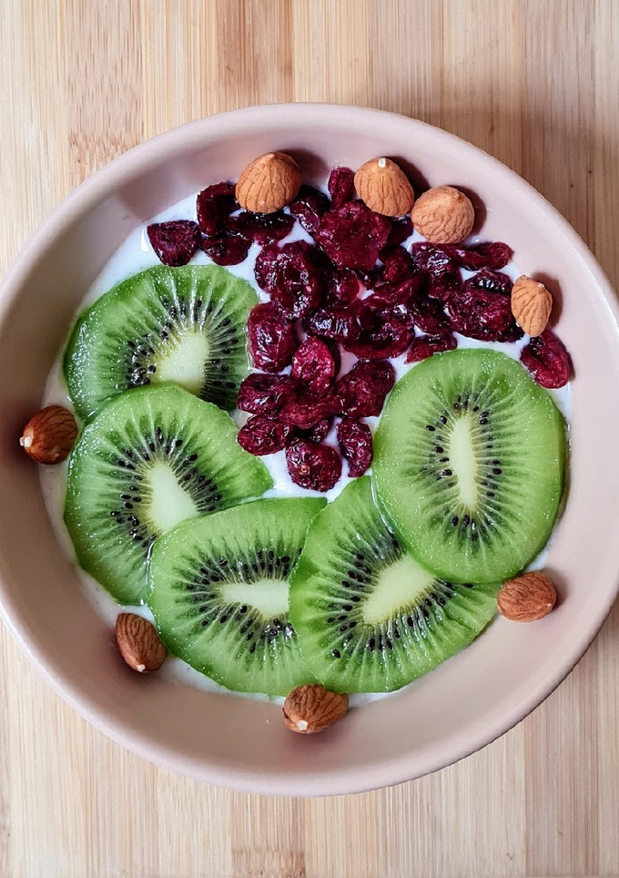 Una foto de Smoothie bowl de yogur de canela, con kiwi fresco, cranberries y almendras remojadas