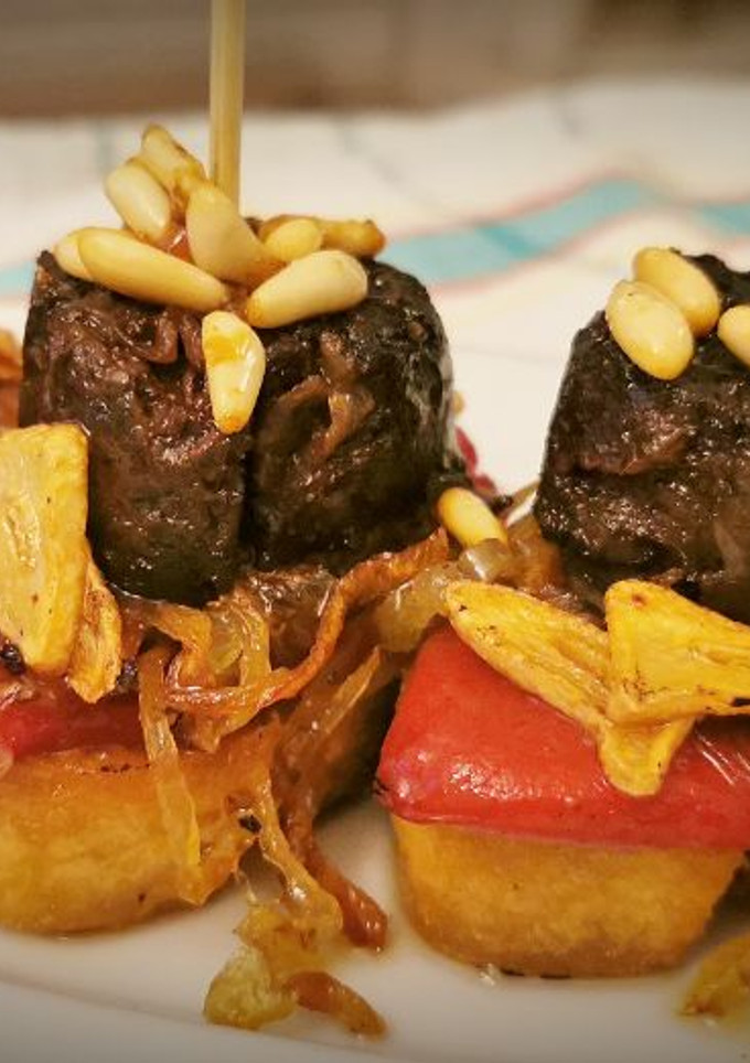 Una foto de Pincho de Morcilla con Piquillos, Cebolla caramelizada y Piñones