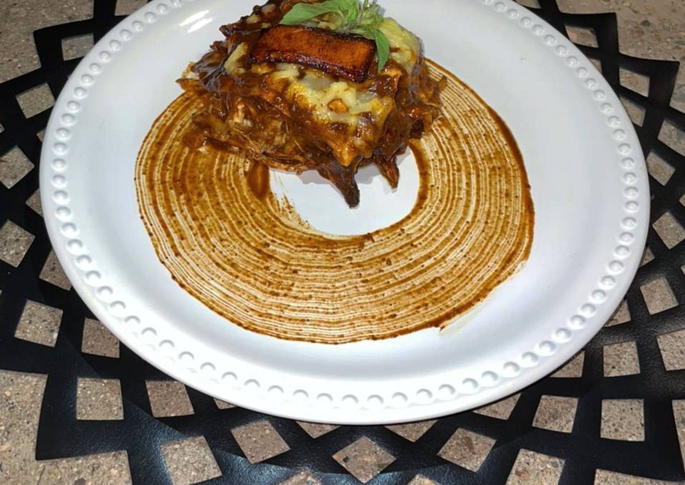 Lasaña de mole coloradito con pollo y frituras de plátano macho