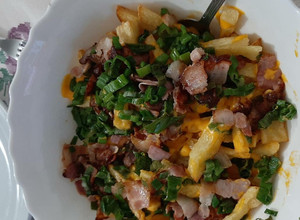 Una foto de Papas fritas con cheddar y bacon