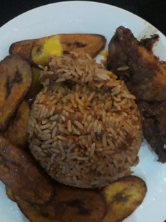 A picture of Jellof rice, plantain and chicken.