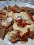 Milanesa con tomate, tiras de morrón y queso