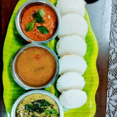 A picture of Idli with Sambar and Chutney.