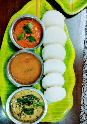 A picture of Idli with Sambar and Chutney.