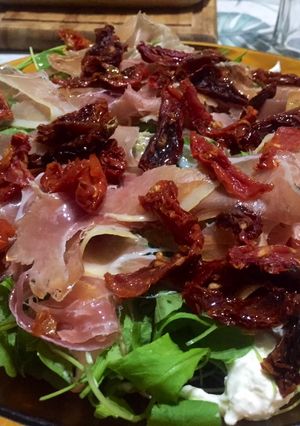 Una foto de Ensalada de Burrata, rúcula, tomates secos y jamón crudo