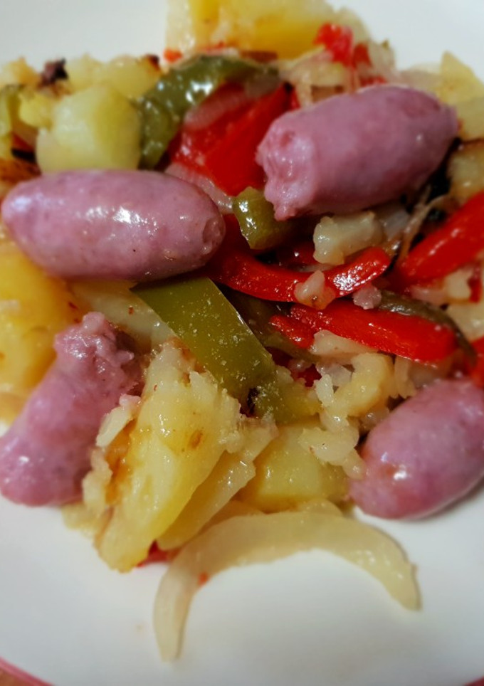 Una foto de Salchipatatas confitadas con pimientos y cebolla