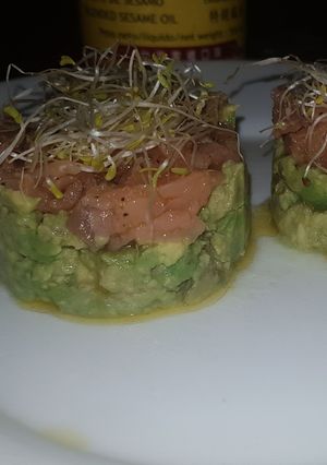 Una foto de Tartar de salmón y aguacate con aceite de sésamo y alfalfa