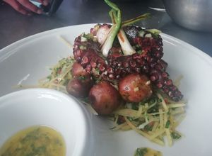 Una foto de Pulpo a la parrilla con ensalada de papaya verde y papas coktail