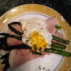 A picture of Asparagus topped with poached egg.