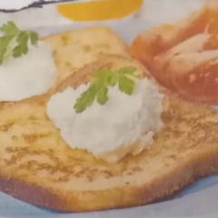 A picture of French toast served with sour cream and fresh tomato.