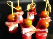 Una foto de brocheta de tomate, jamon