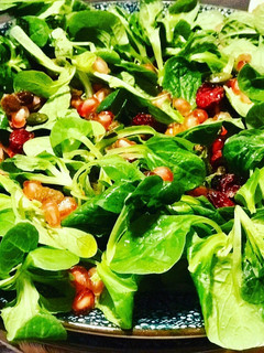 Una foto de Ensalada de canónigos, granada, frutos secos y arándanos