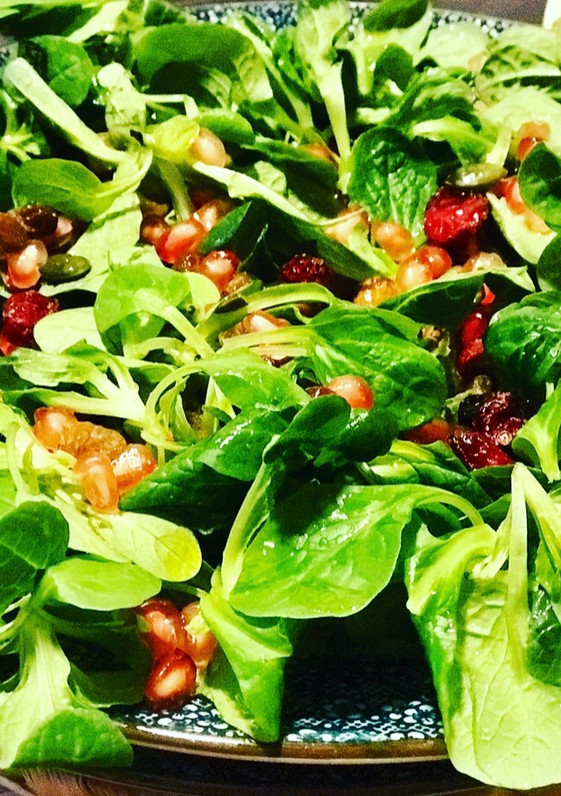 Una foto de Ensalada de canónigos, granada, frutos secos y arándanos