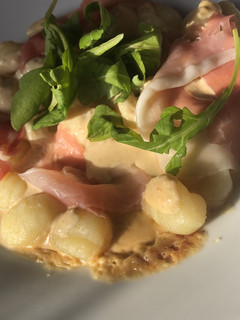 Una foto de Ñoquis con salsa de queso, prosciutto y rúcula