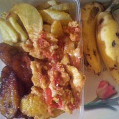 A picture of Fried potatoes/plantain and egg sauce plus banana.