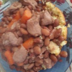 A picture of Pinto beans with pork over cornbread.
