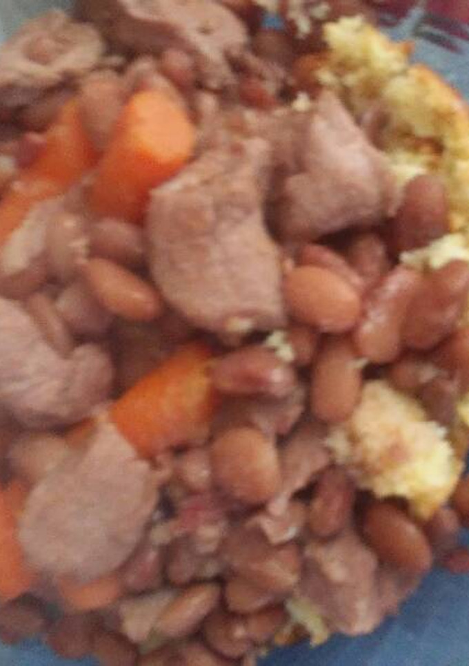 A picture of Pinto beans with pork over cornbread.